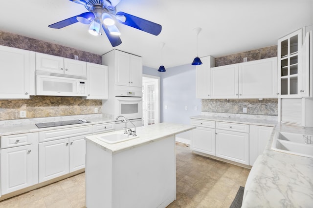 kitchen featuring tasteful backsplash, glass insert cabinets, white cabinets, a sink, and white appliances