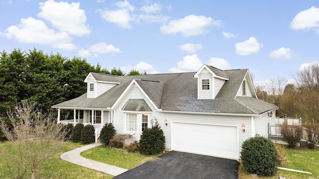 view of front of house featuring a porch, a garage, a shingled roof, driveway, and a front lawn