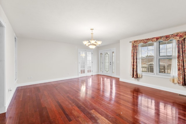 interior space with baseboards, french doors, hardwood / wood-style flooring, and an inviting chandelier