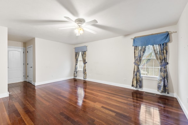 spare room with ceiling fan, wood-type flooring, visible vents, and baseboards