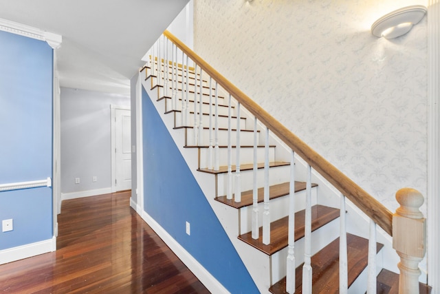 staircase with wood finished floors, baseboards, and wallpapered walls