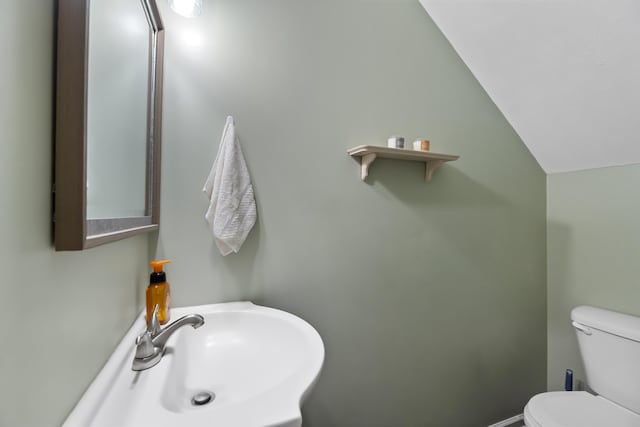 bathroom featuring toilet, lofted ceiling, and sink