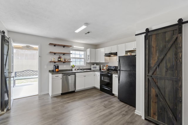 kitchen featuring black appliances, dark hardwood / wood-style floors, a barn door, and white cabinets