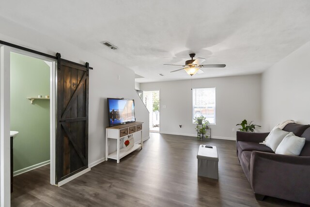 living room with ceiling fan, a barn door, and dark hardwood / wood-style floors