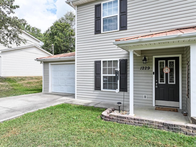 view of exterior entry with a garage and a yard