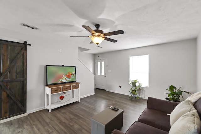 living room featuring a barn door, ceiling fan, and dark hardwood / wood-style floors