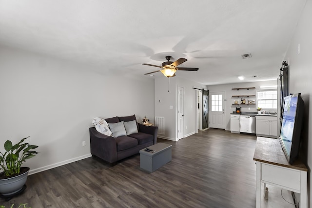 living room with ceiling fan, a barn door, dark hardwood / wood-style flooring, and sink