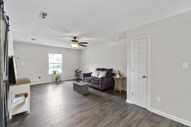 living room with a barn door, ceiling fan, and dark hardwood / wood-style floors