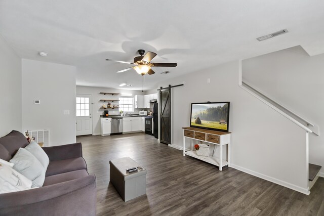 living room featuring ceiling fan, a barn door, and dark hardwood / wood-style flooring