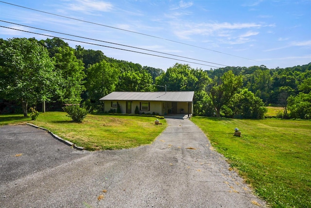 2368 Hall Rd, Dandridge, TN 37725 - view of front facade featuring asphalt driveway, a forest view, an attached carport, a front lawn, and a metal roof