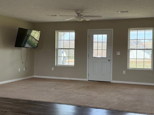 interior space with a healthy amount of sunlight, a textured ceiling, a ceiling fan, and wood finished floors