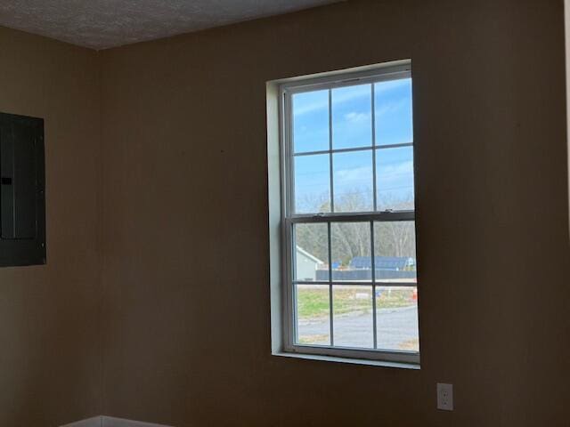 spare room with electric panel and a textured ceiling