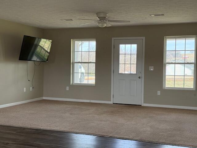 interior space featuring a ceiling fan, baseboards, a wealth of natural light, and a textured ceiling