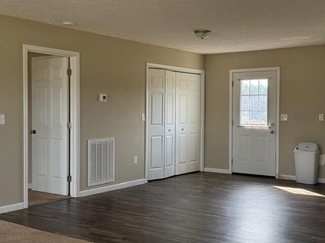 unfurnished bedroom with visible vents, baseboards, and dark wood-style floors