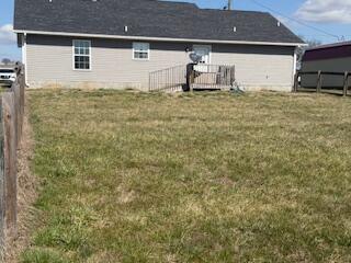 back of property featuring a yard and fence