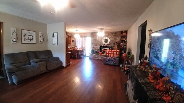 living room featuring a stone fireplace and dark wood-type flooring