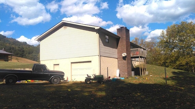 view of side of home with a wooden deck, a yard, and a garage