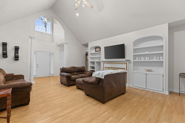 living room with built in shelves, light hardwood / wood-style flooring, high vaulted ceiling, and ceiling fan with notable chandelier