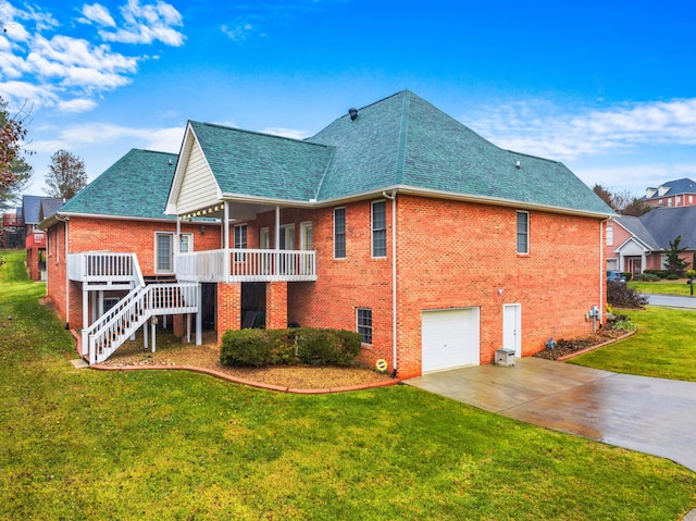 rear view of property with a lawn, a deck, and a garage