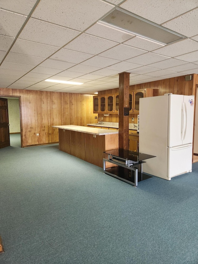 kitchen featuring kitchen peninsula, carpet, a paneled ceiling, wooden walls, and white fridge