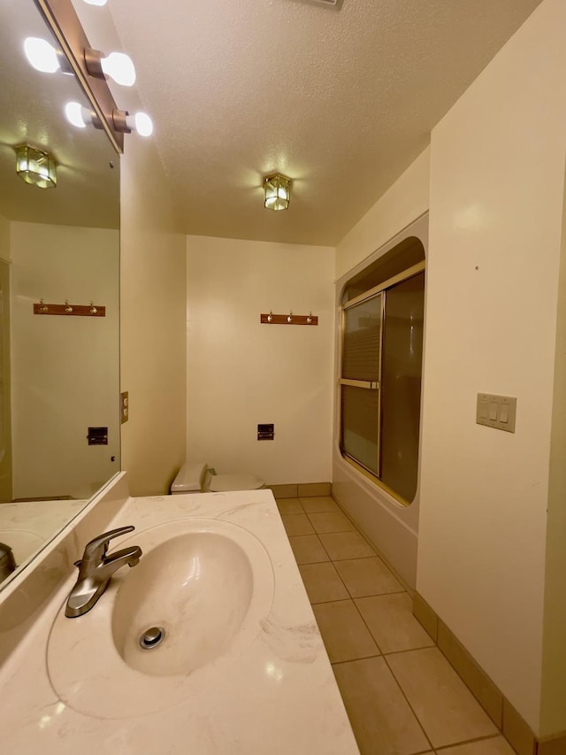 full bathroom featuring vanity, combined bath / shower with glass door, tile patterned flooring, toilet, and a textured ceiling