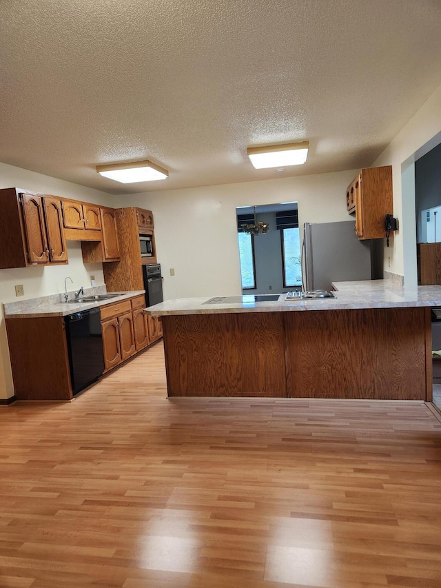 kitchen featuring sink, kitchen peninsula, light hardwood / wood-style floors, a textured ceiling, and black appliances