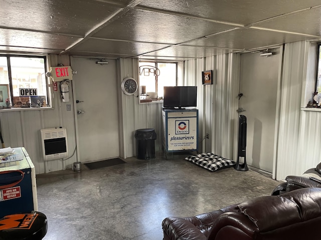 living room with concrete floors, heating unit, and wood walls