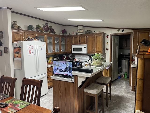 kitchen featuring lofted ceiling, a kitchen bar, and white appliances