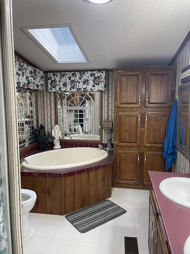 bathroom with vanity, a textured ceiling, a skylight, and a washtub