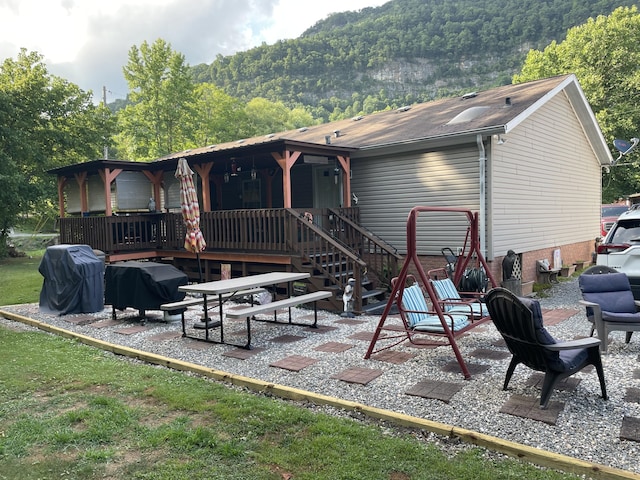 back of property with a mountain view and a patio