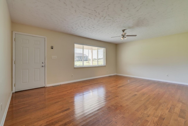 empty room featuring ceiling fan, light wood-type flooring, and a textured ceiling