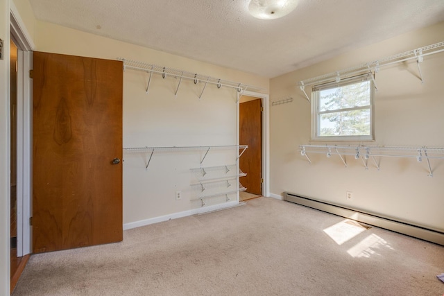 spacious closet with carpet flooring and a baseboard heating unit