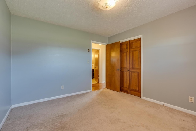 unfurnished bedroom with light colored carpet, a textured ceiling, and a closet