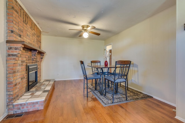 dining room featuring a fireplace, wood-type flooring, and ceiling fan