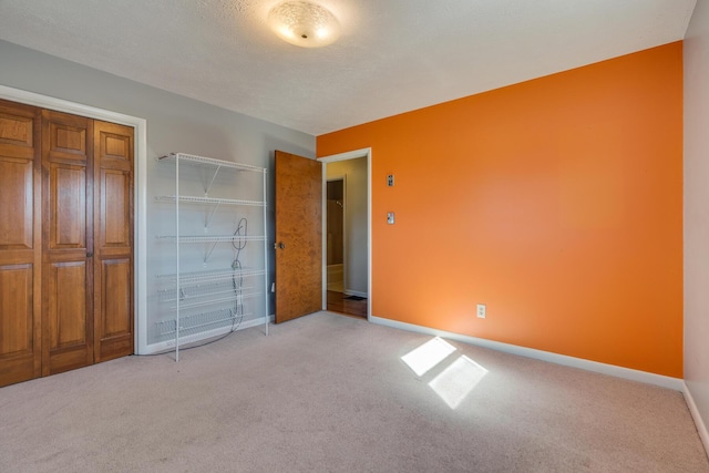 unfurnished bedroom with light colored carpet, a textured ceiling, and a closet