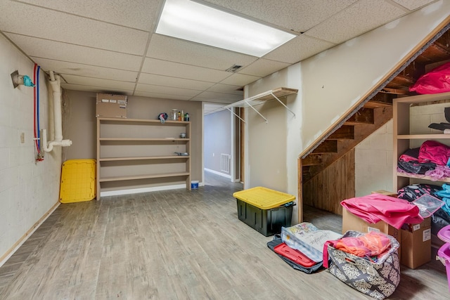 basement with a paneled ceiling and wood-type flooring