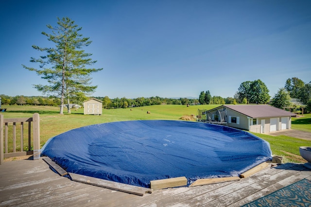 view of pool with a yard, a shed, and a deck