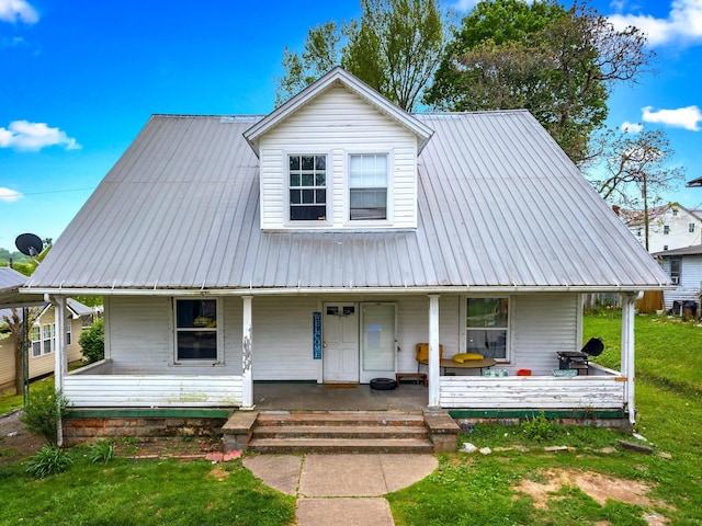 view of front facade featuring fence, metal roof, a front yard, and a porch