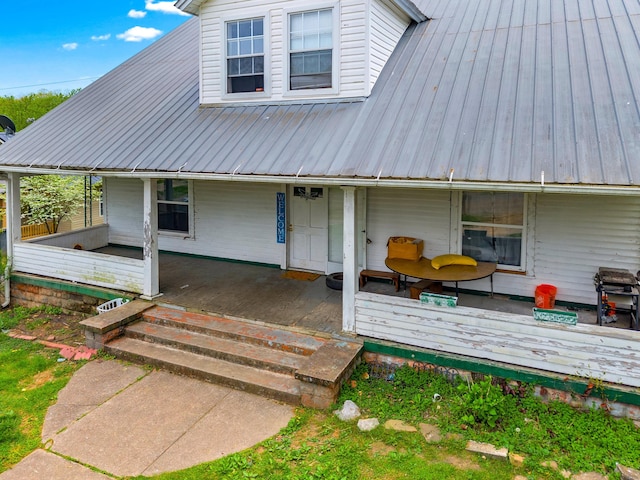 rear view of property with covered porch and metal roof