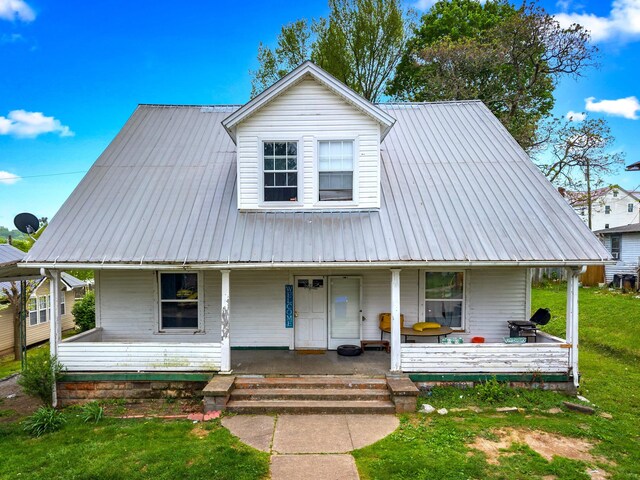 view of front of house with a porch, a front yard, and metal roof