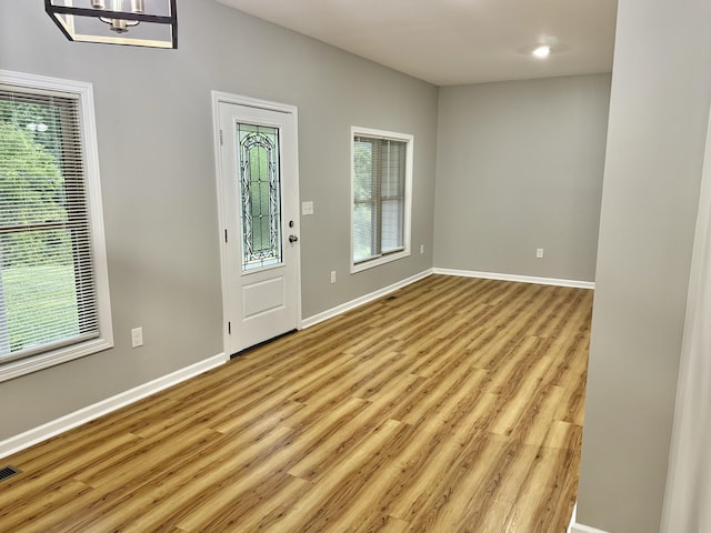 foyer entrance featuring light hardwood / wood-style flooring, a healthy amount of sunlight, and a notable chandelier