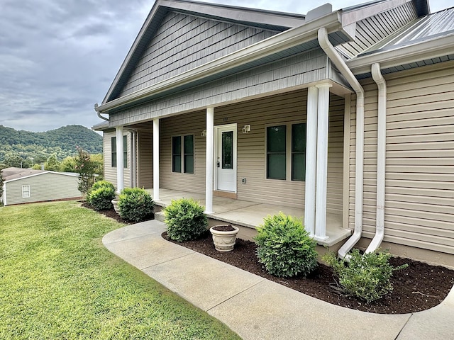 entrance to property featuring a mountain view, a porch, and a yard