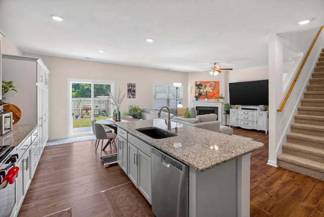 3059 Berna Way, Morristown, TN 37814 - kitchen with stainless steel appliances, a fireplace, a ceiling fan, a center island with sink, and light stone counters