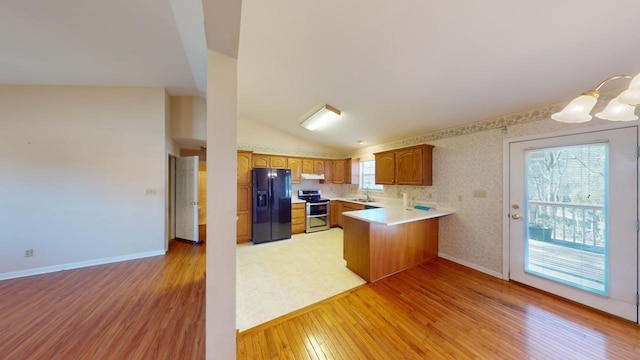 kitchen with sink, black fridge, light hardwood / wood-style flooring, kitchen peninsula, and range with two ovens