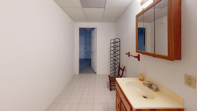 bathroom with a drop ceiling, vanity, and tile patterned flooring