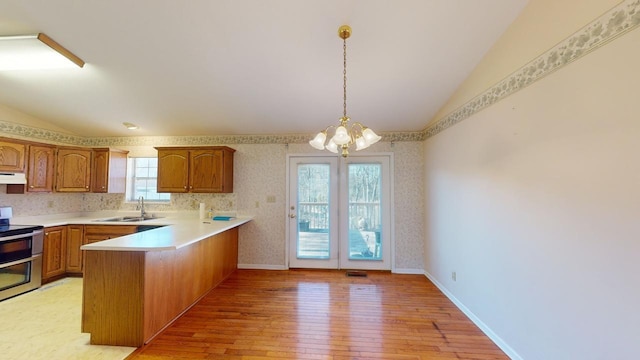 kitchen featuring stainless steel electric stove, vaulted ceiling, pendant lighting, sink, and kitchen peninsula