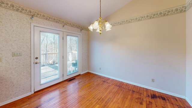 interior space featuring an inviting chandelier, lofted ceiling, and hardwood / wood-style floors