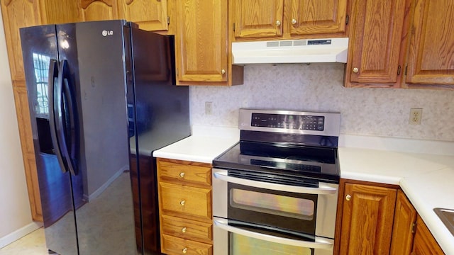 kitchen with decorative backsplash, black refrigerator with ice dispenser, and range with two ovens