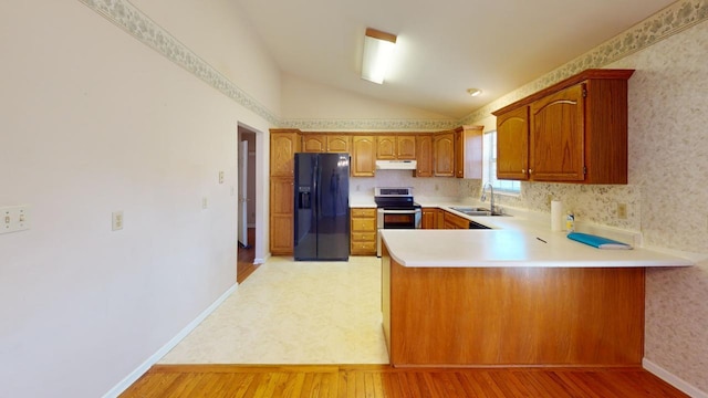 kitchen with sink, light hardwood / wood-style flooring, stainless steel range with electric stovetop, black fridge, and kitchen peninsula