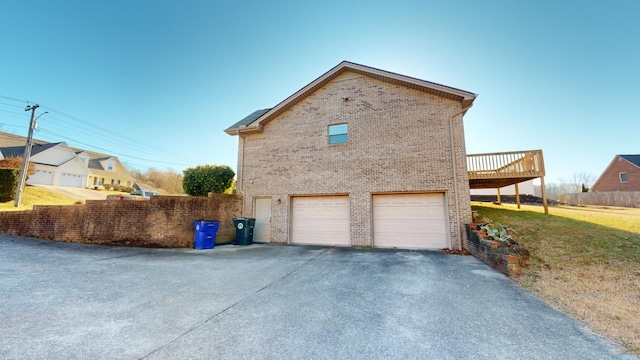 view of side of property with a wooden deck, a garage, and a lawn